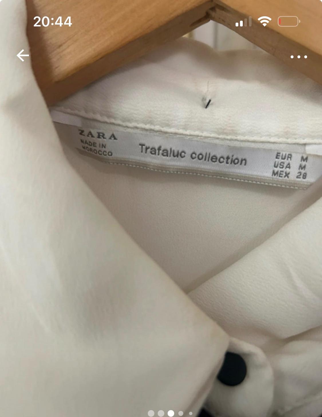 Label from a white garment from Zara's Trafaluc collection, made in Morocco, with sizes EUR M, USA M, MEX 28, on a wooden hanger.