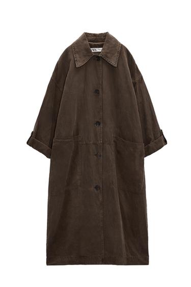 Dark brown long coat with a collar, front buttons, pockets and rolled-up sleeves. Label with ZARA text on a white background.