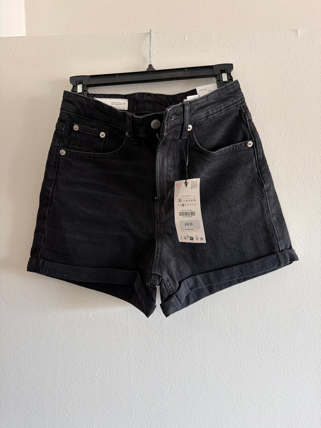 Black denim shorts hanging on a hanger, with visible tag showing the price of £45.90, against a white background.
