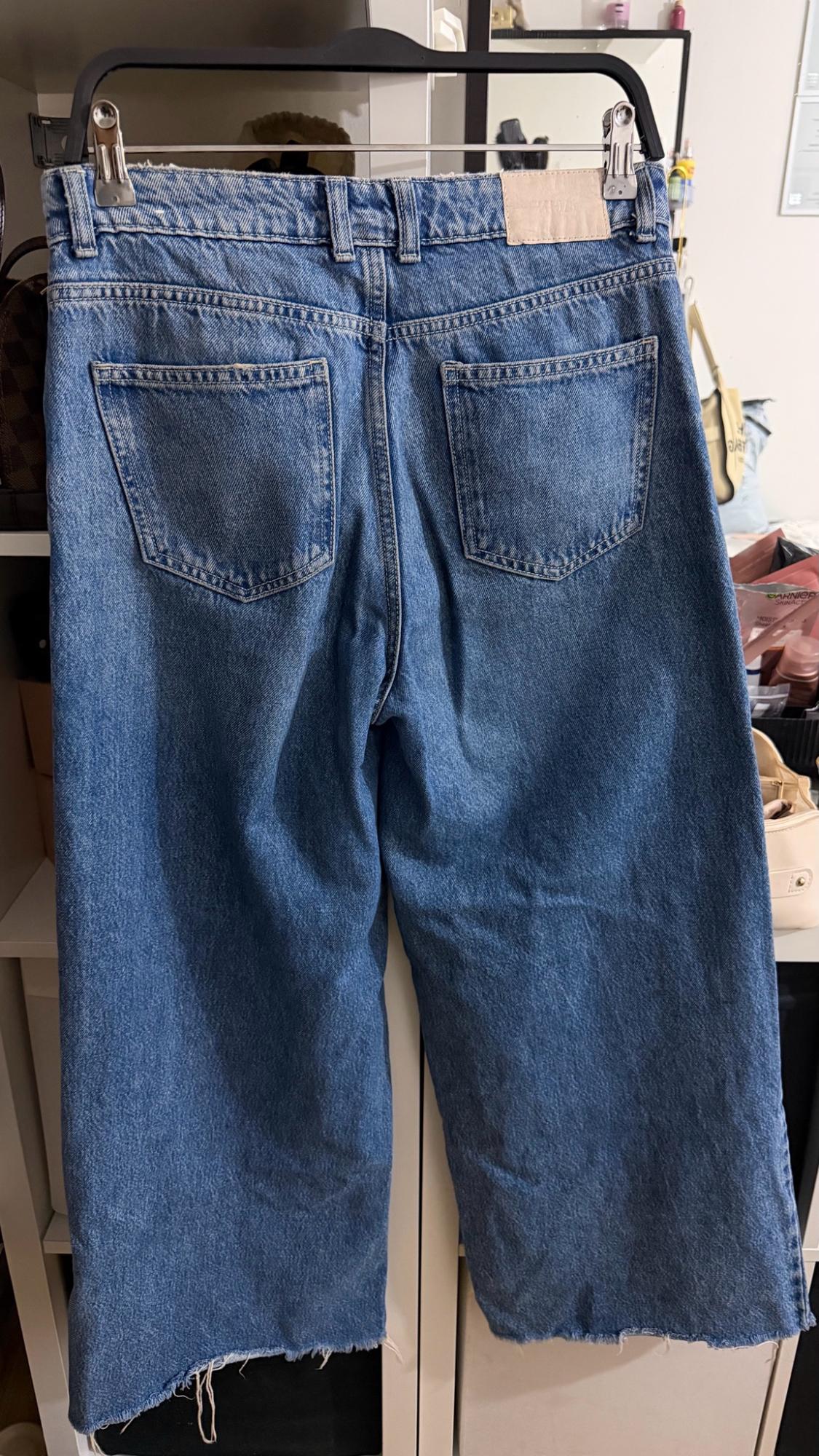 Blue denim jeans hung from the back, showing pockets and a frayed hem. In the background, objects and a box with the text GARNIER SkinActive.