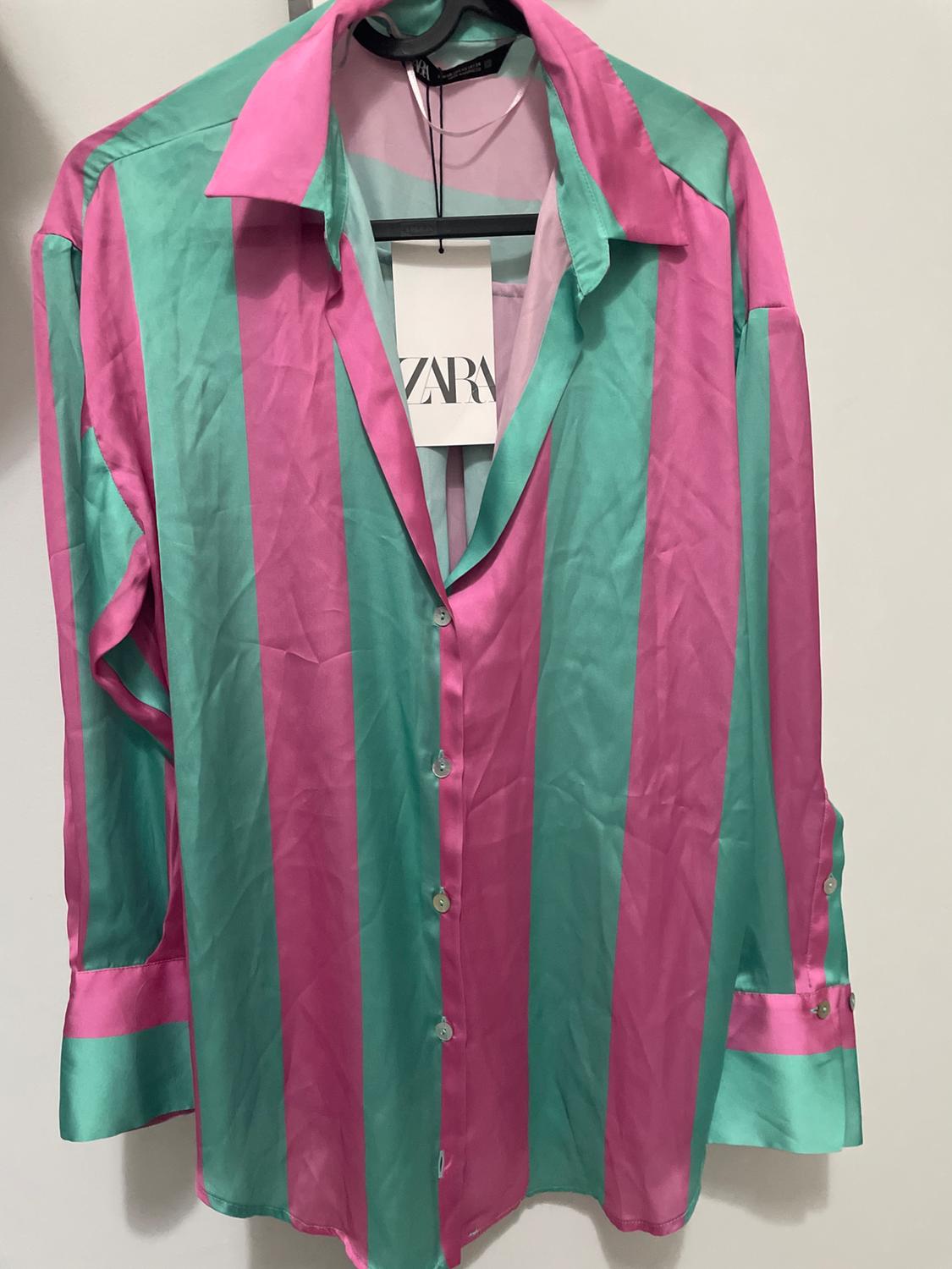 Vertical striped shirt in pink and green, hanging on a hanger. Visible label with the text "ZARA".