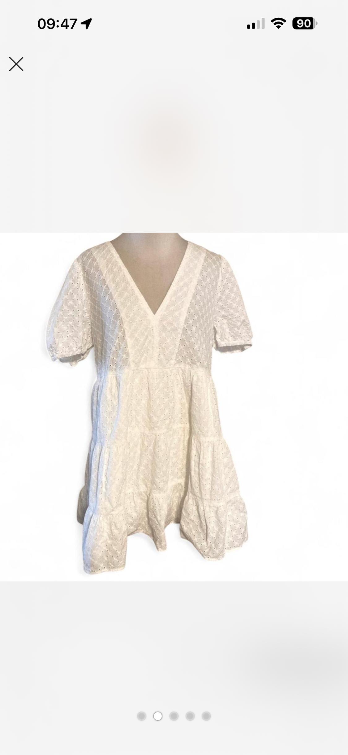 White dress with short sleeves and V-neck, knitted with a lace pattern. White background, mobile phone screen image.