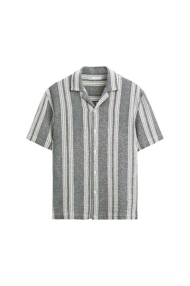 Short-sleeved shirt with black and white vertical stripes, lapel collar, and button front closure, shown against a white background.