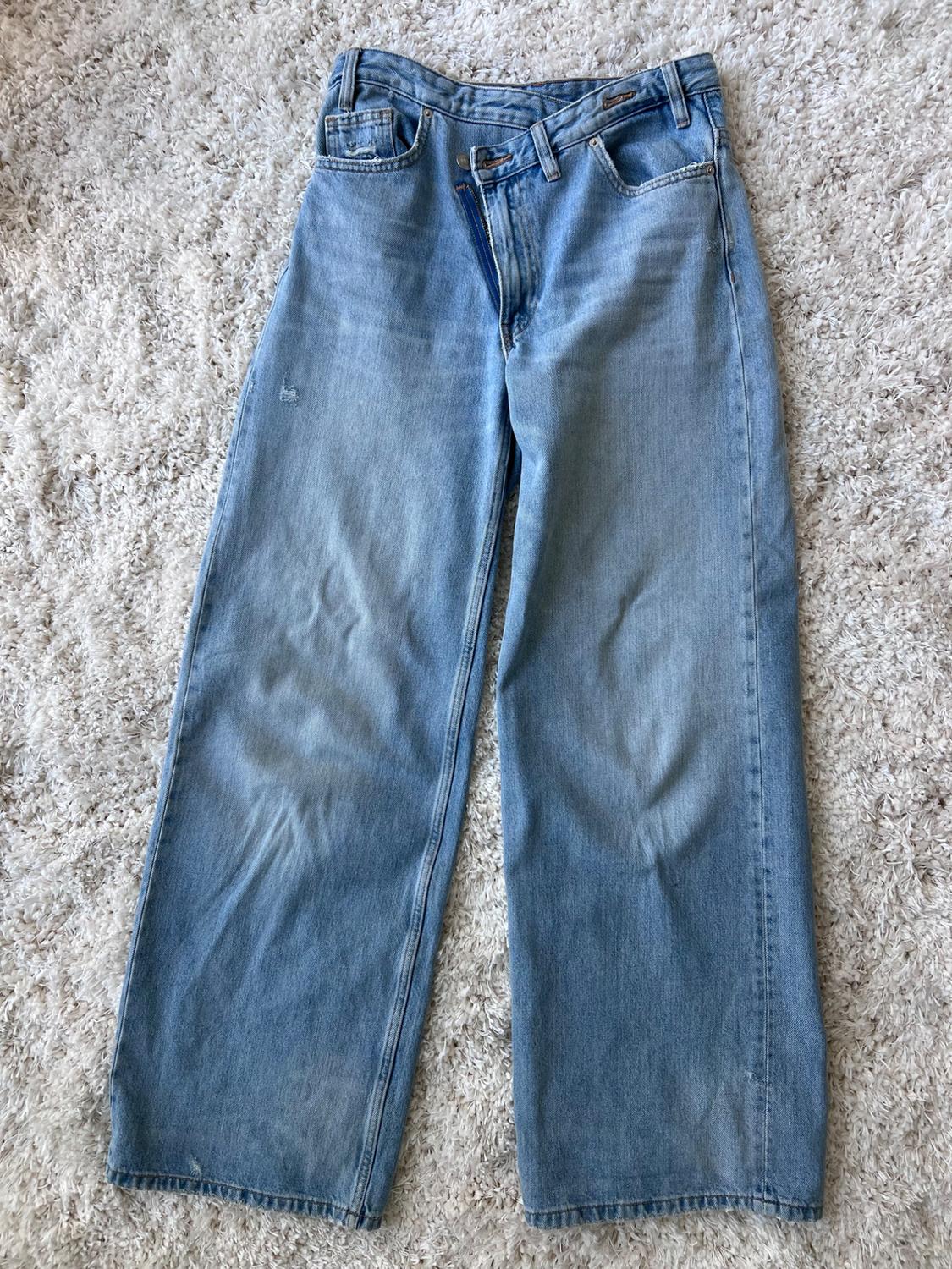 Light blue denim straight-cut jeans, placed on a soft-textured beige rug.
