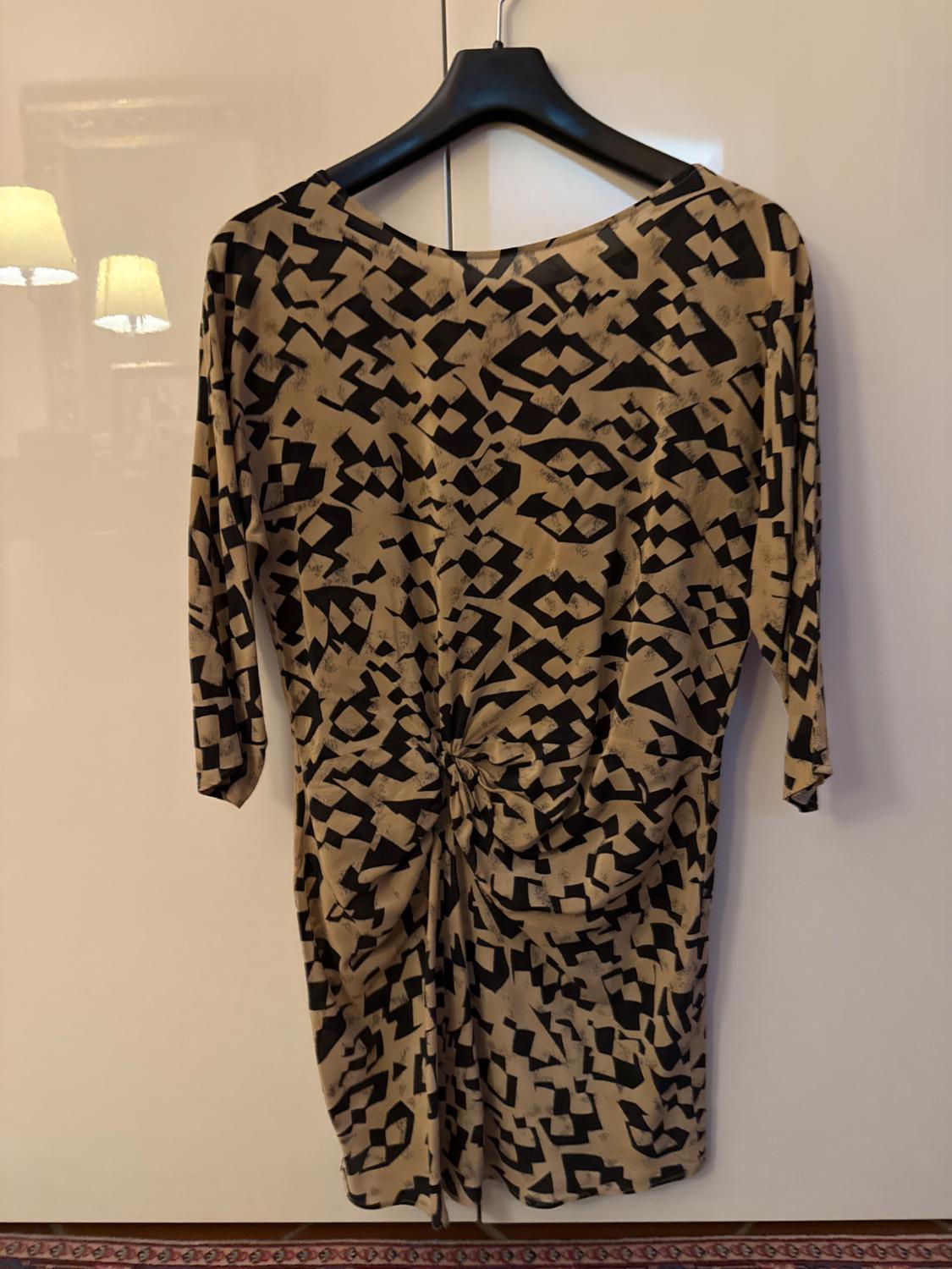 Front view of a black and beige geometric print dress with long sleeves and a gathered waist.