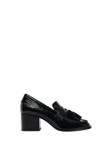 Black patent-leather loafer with a block heel and tassel detail at the front, on a white background.