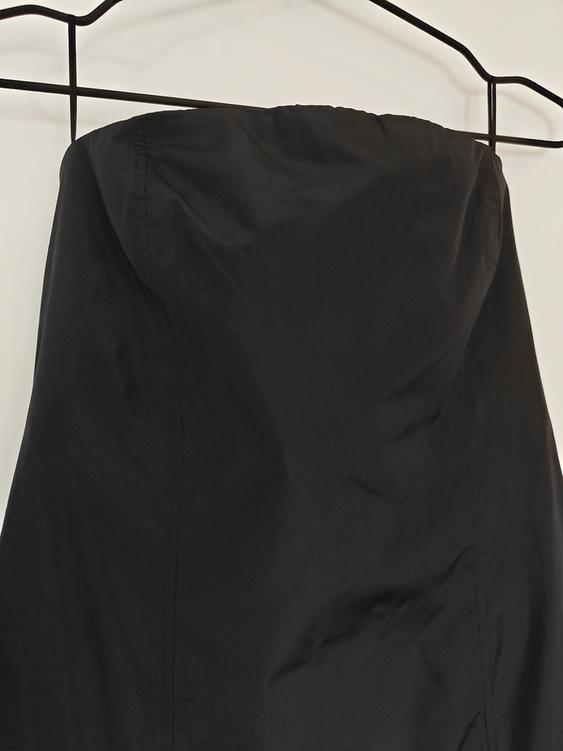Black strapless dress hanging on a black hanger against a white background.