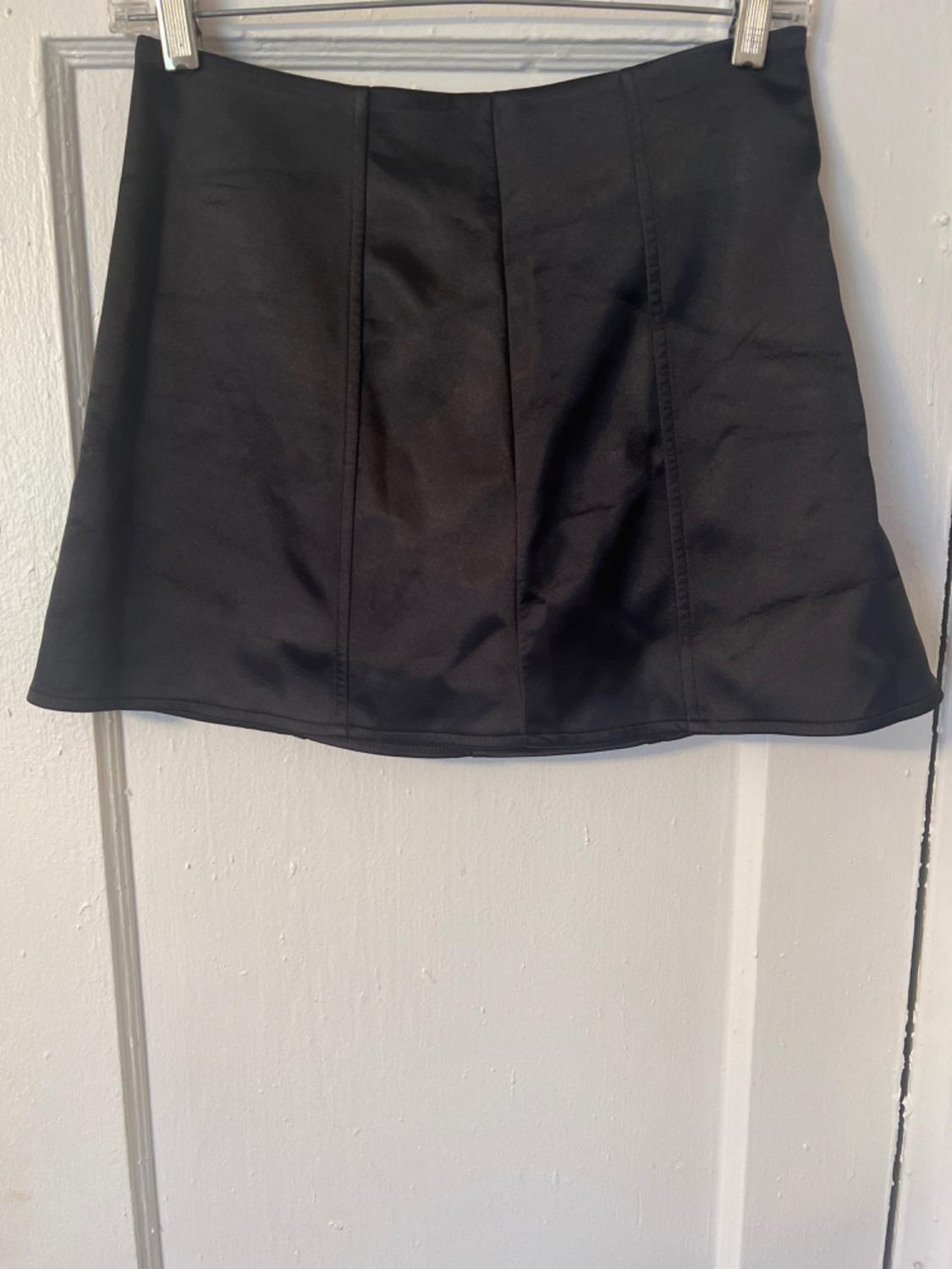 Front view of a black skirt with visible seams.