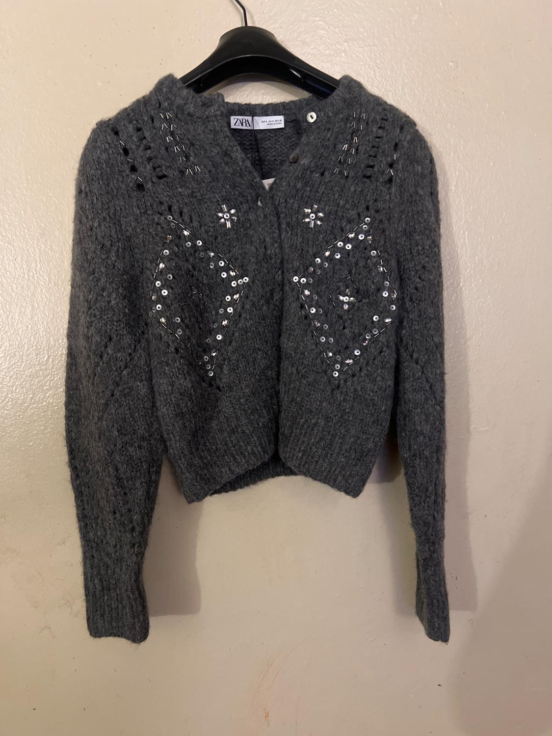 Front view of gray sweater with sequins and diamond pattern on the chest.