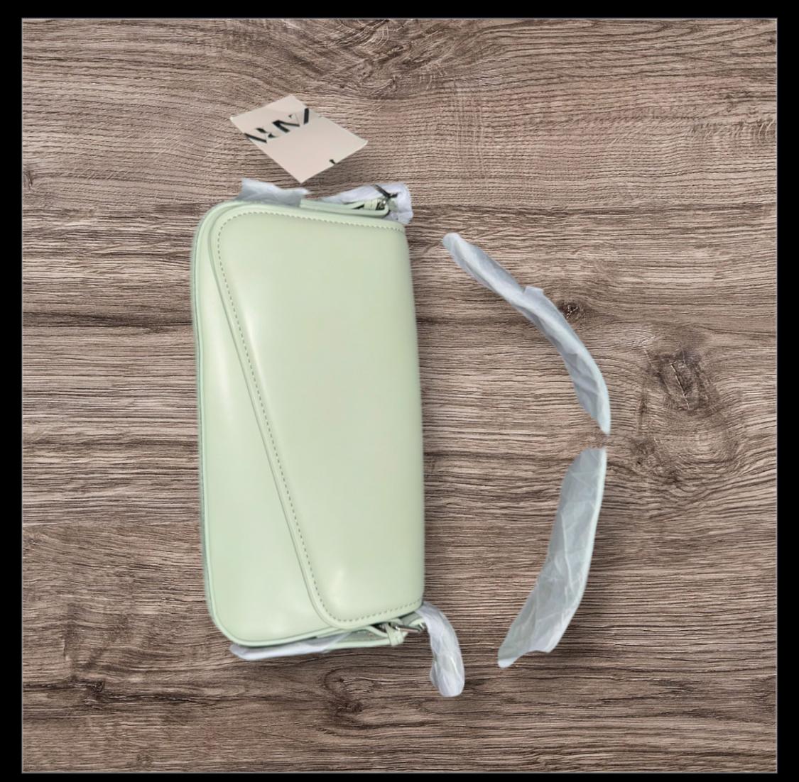 Front view of a light green rectangular pocket with a zip closure and a visible label.