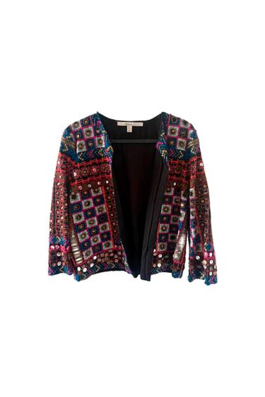 Colourful jacket with geometric patterns and sparkling details on a white background. Visible label on the collar.