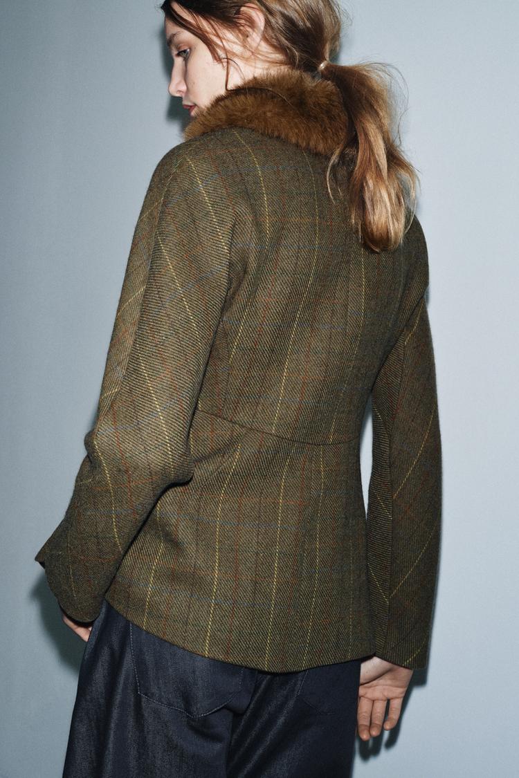 Srednji posnetek toplega blazerja z ovratnikom z reverji in aplikacijo z učinkom krzna, dolgimi rokavi in našitimi žepi.