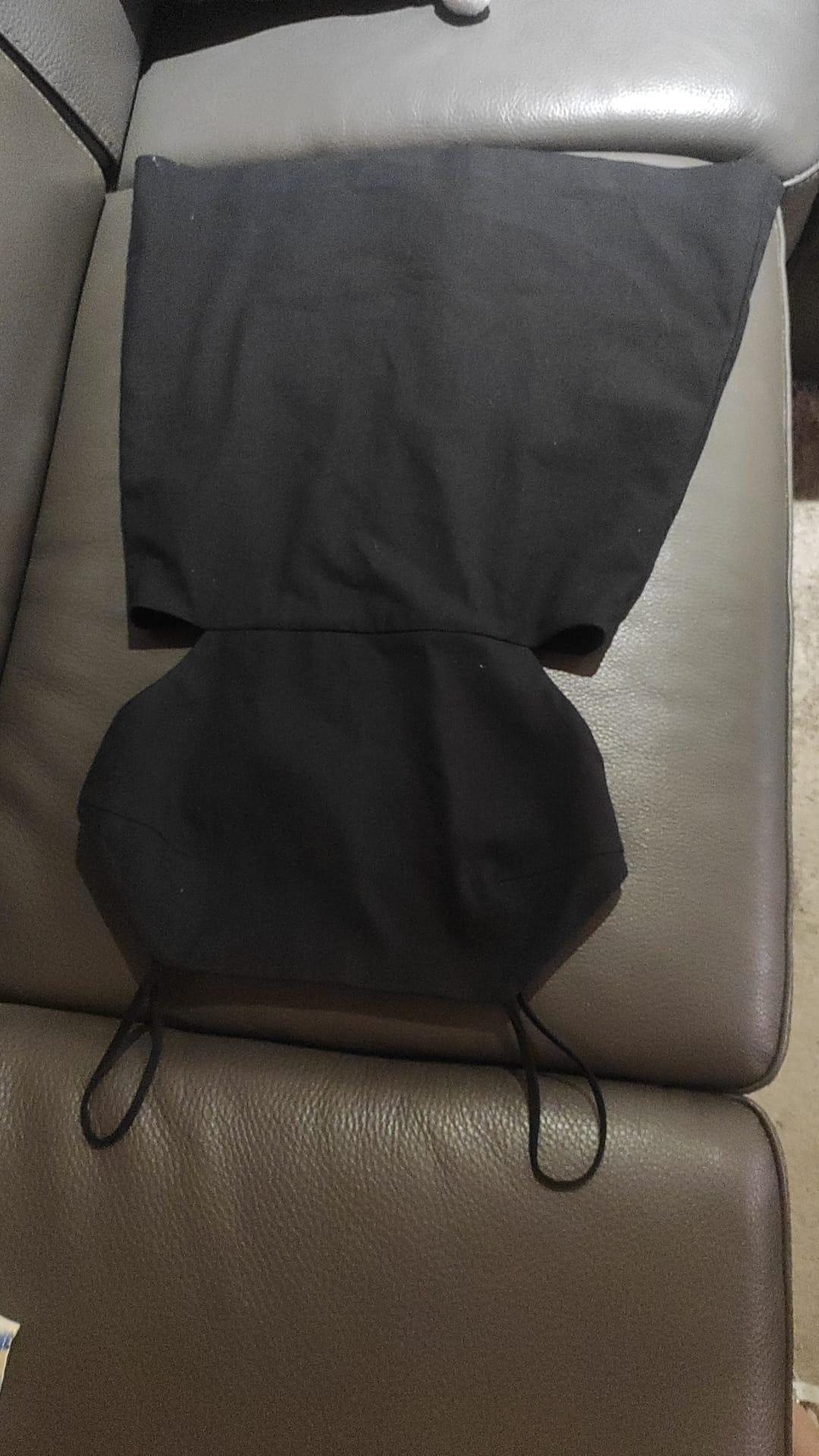 Black camisole top with thin straps and side slits, laid out on a grey leather sofa.