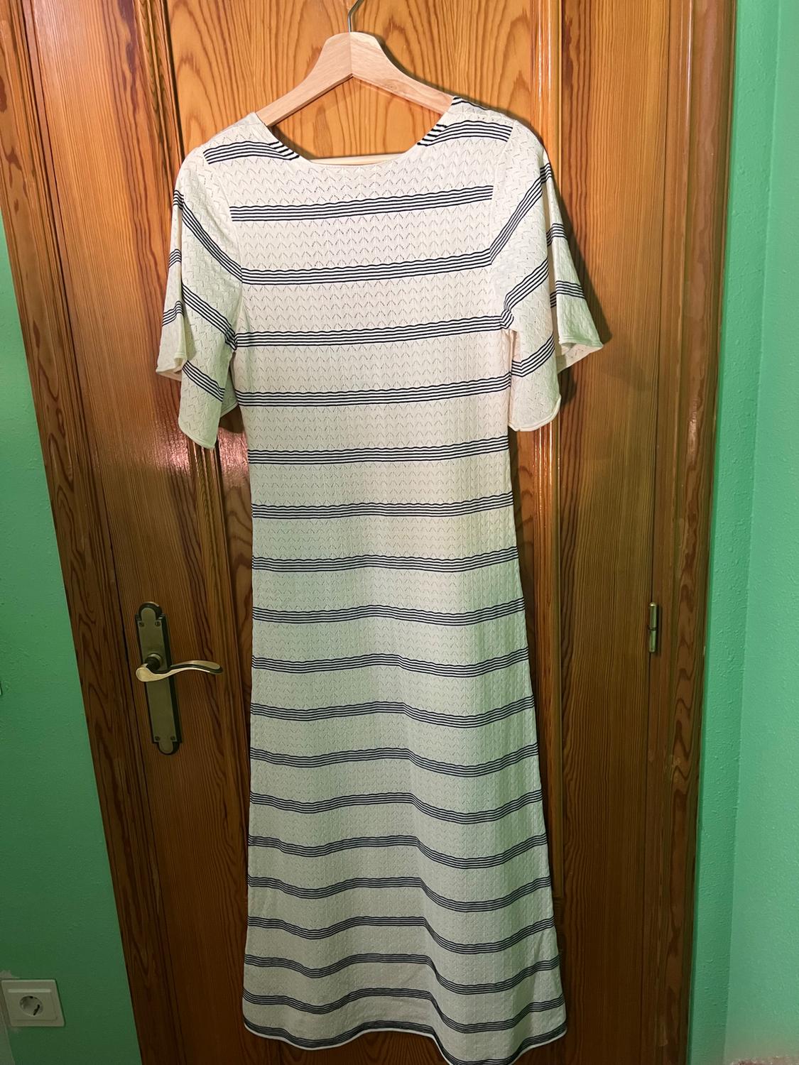 Blue and white horizontal striped dress hanging on a wooden hanger over a light wooden door.