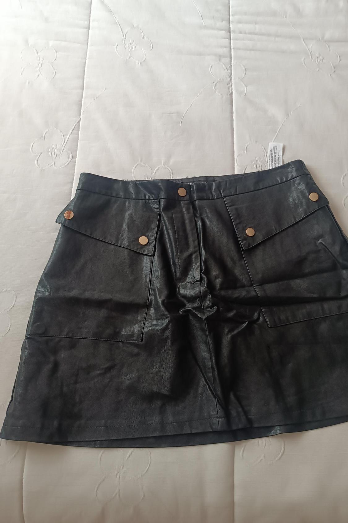 Front view of a black skirt with front flap pockets and gold buttons.