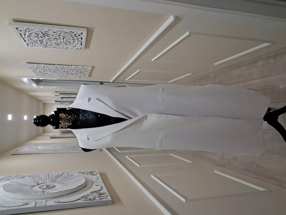 Mannequin with a long white gilet in a corridor decorated with artistic wall panels. Elegant and modern ambience.