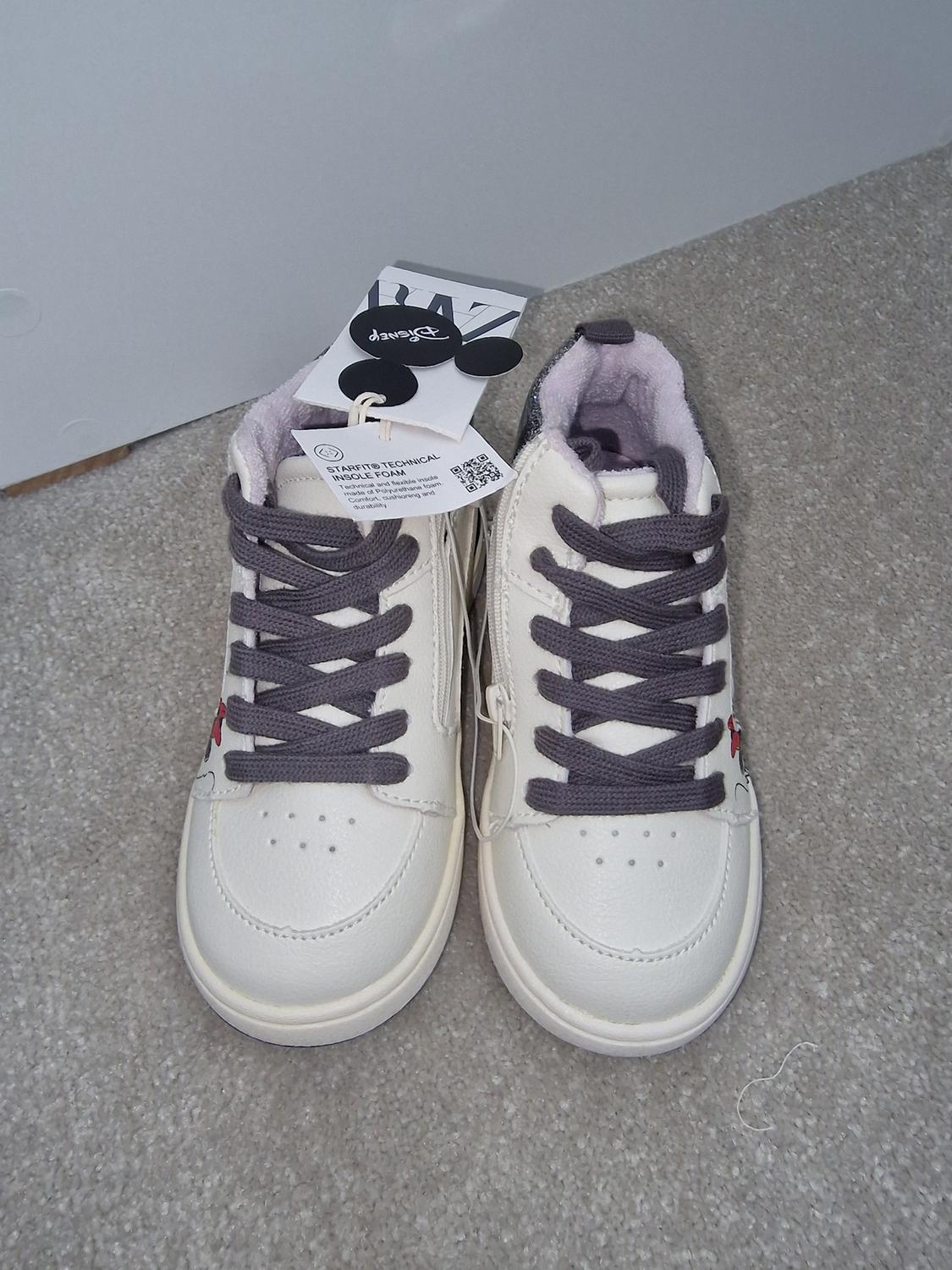 White trainers with grey laces on a beige carpet. Label visible with text: "STARTING TECHNICAL INSOLE FOAM".
