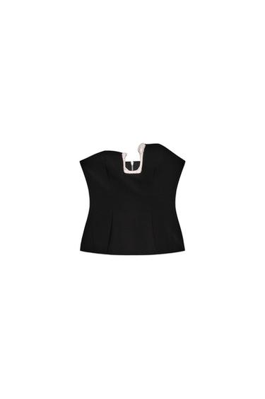 Front view of a black strapless top with a straight neckline, decorative metal piece, and visible seams.