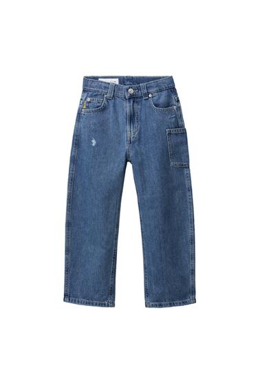 Front view of medium blue denim trousers for a boy with side pockets and distressed detail on the left leg.