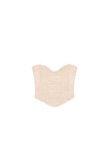 Front view of a beige corset with ruching and a fitted structure.