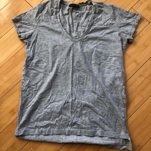 Gray short-sleeved V-neck t-shirt with a wrinkled, relaxed look, laid out on a wooden plank floor.