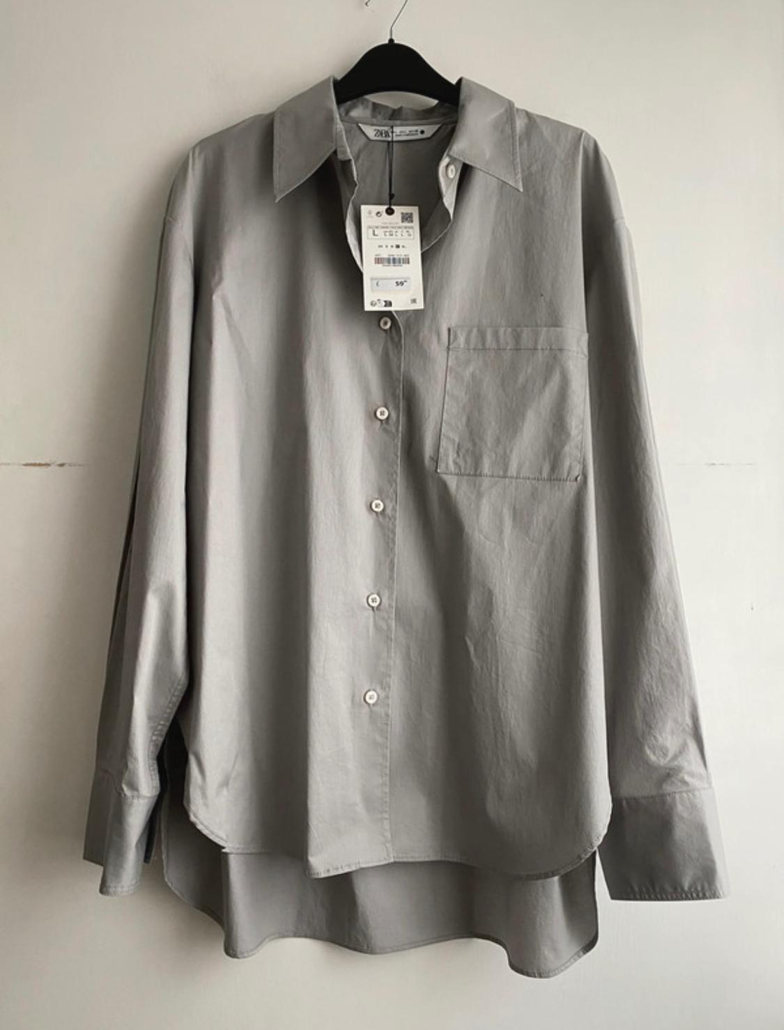 Front view of grey shirt with top left pocket and white buttons.