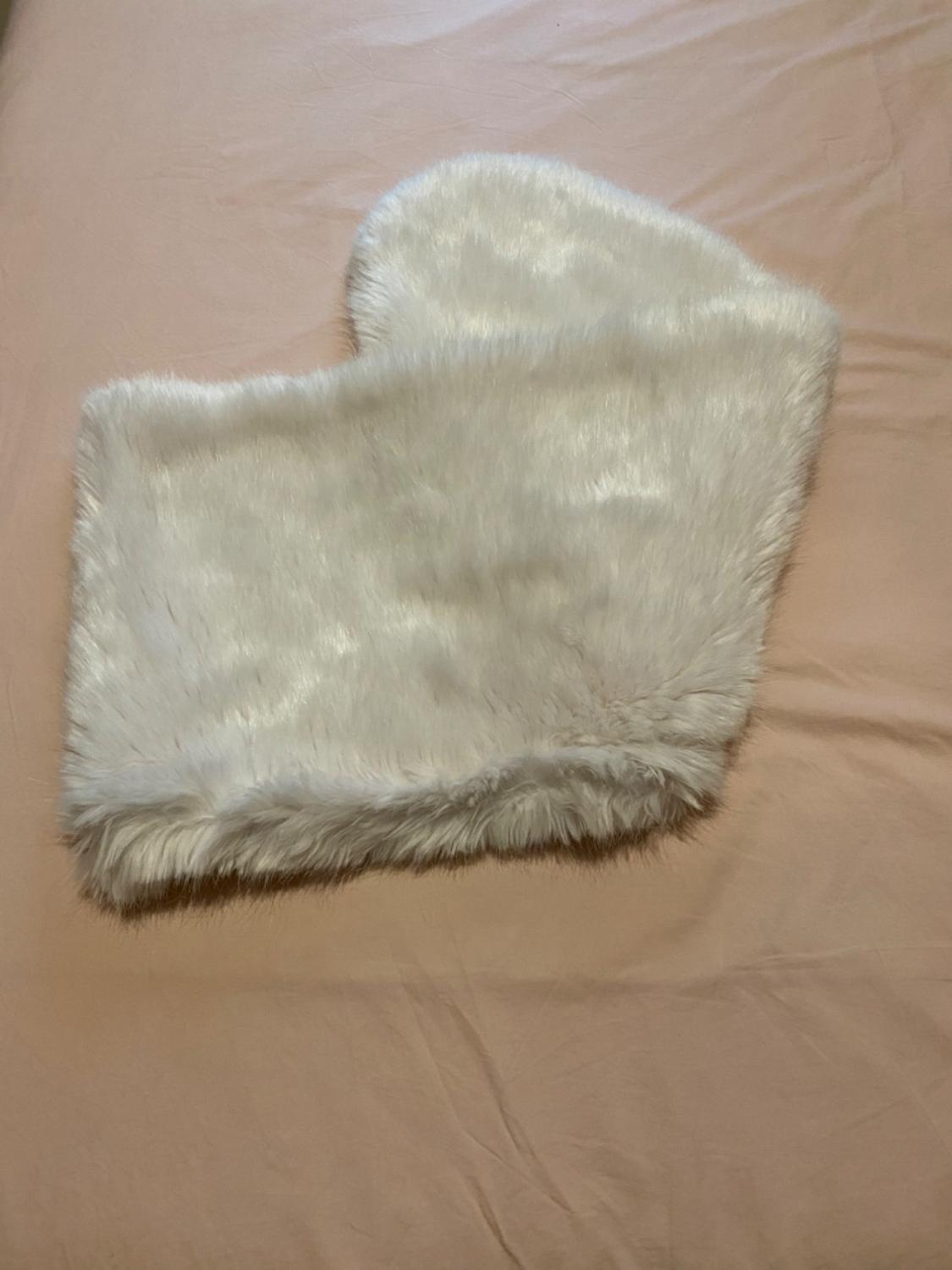 Front view of a white plush accessory on a beige surface.