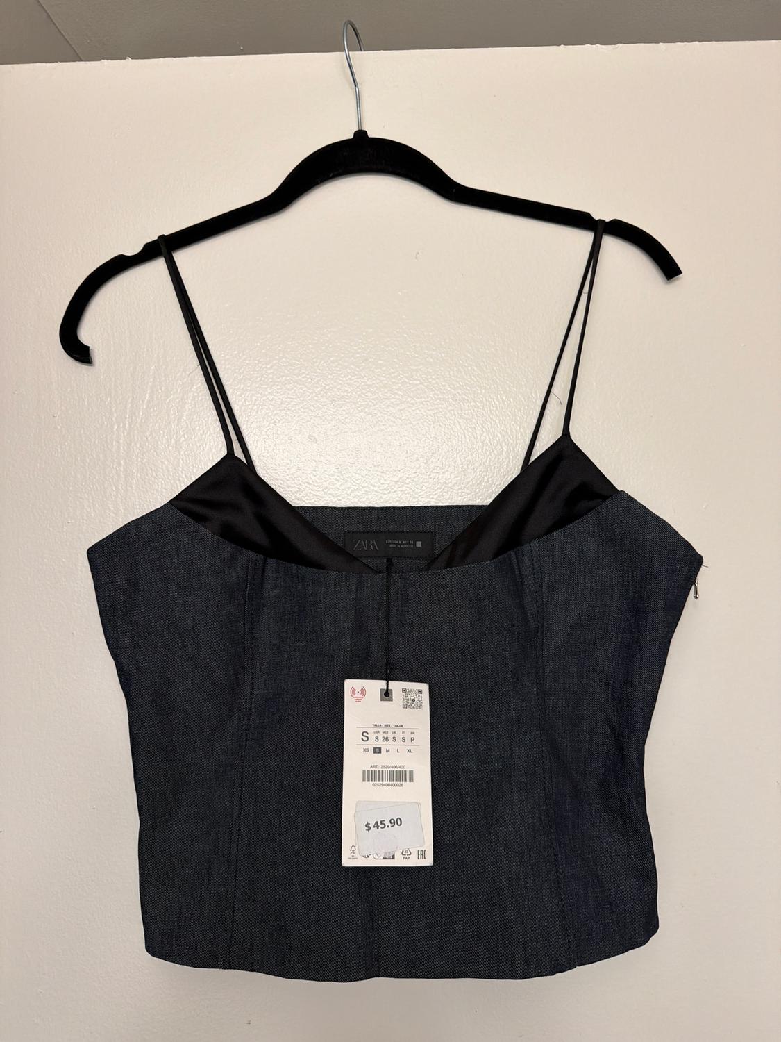 Vestido de tirantes finos en percha negra, color oscuro, con etiqueta de precio de 45,90 $ colgando al frente, fondo blanco.