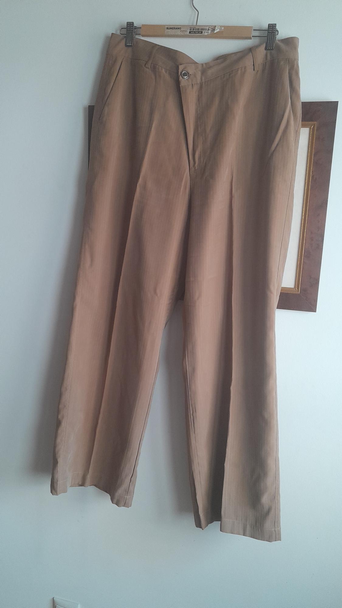 Brown, wide-leg trousers hanging on a wooden hanger against a white wall.
