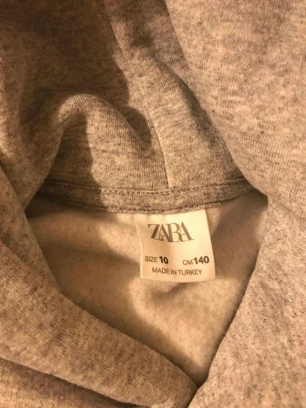 Grey clothing label with the text "ZARA, SIZE 10, CM 140, MADE IN TURKEY" visible on the inside of a garment.