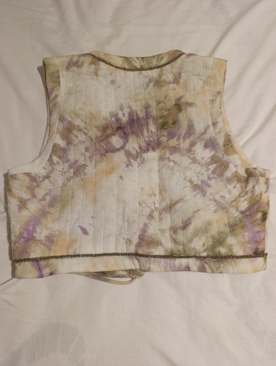 Sleeveless waistcoat with a tie-dye design in shades of purple, beige, and green on a white base.
