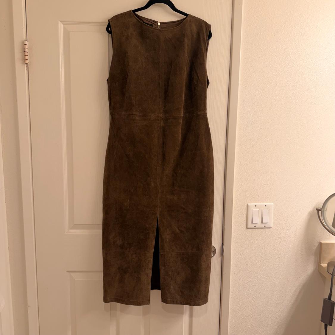 Sleeveless brown dress hanging on a white door. Simple design with a slit at the bottom front.