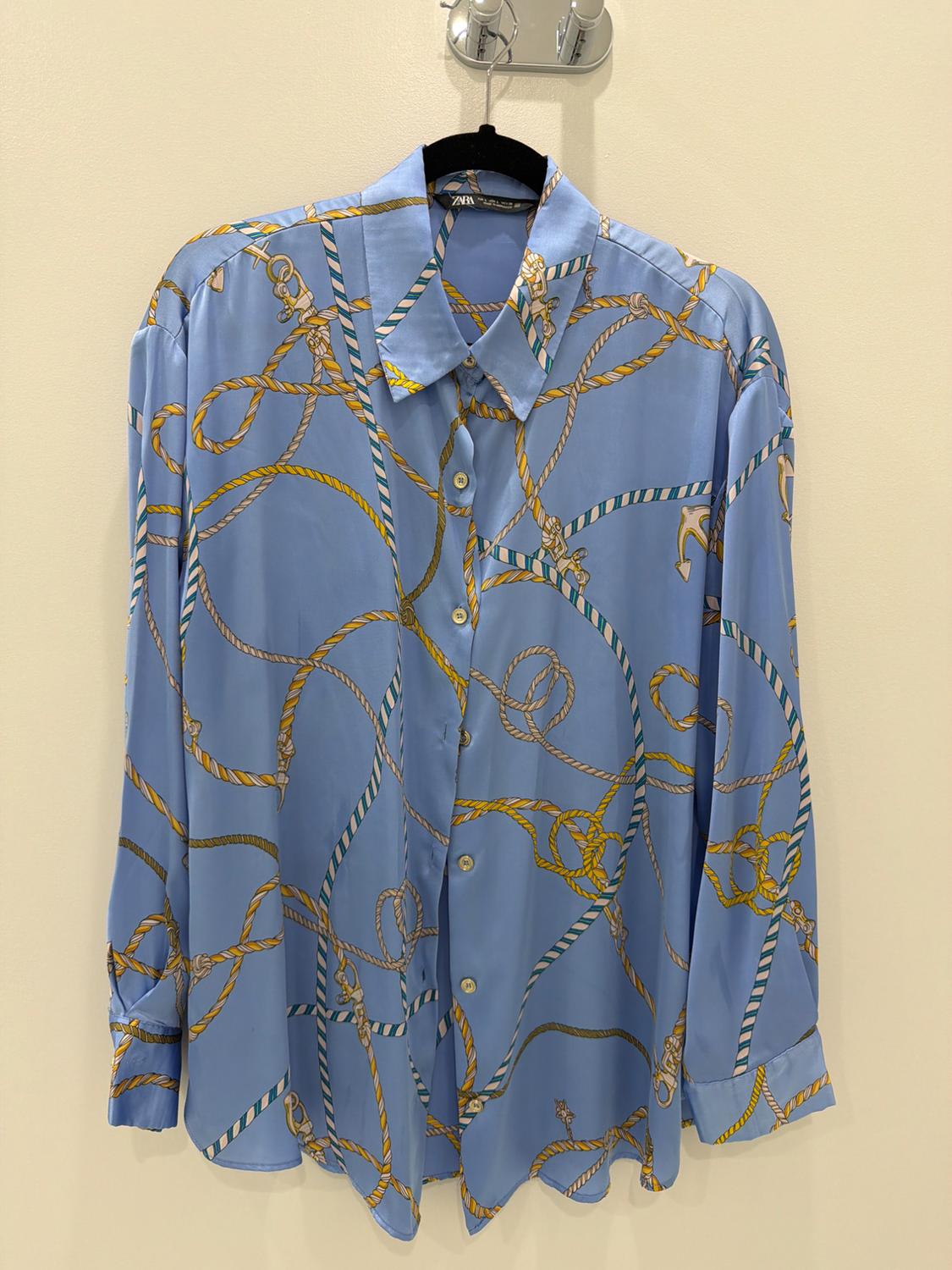 Light blue long-sleeved shirt with a rope and anchor print, hanging on a black hanger against a light background. ZARA label.