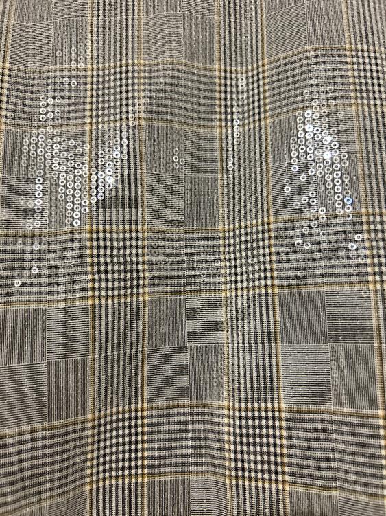 Checked fabric with shimmering sequins in shades of grey and beige, creating a geometric and elegant pattern.