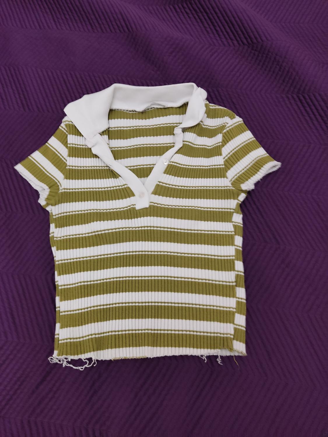 Green and white striped t-shirt with a white collar on a textured purple background.