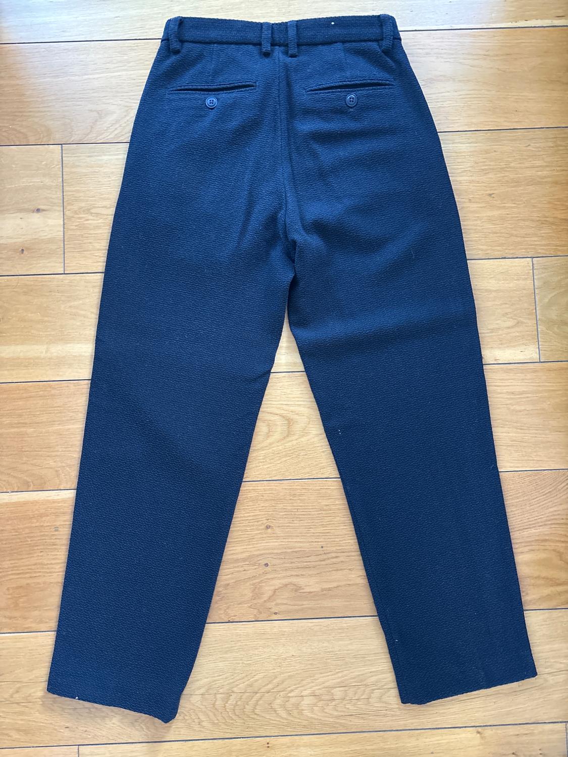 Rear view of navy blue trousers with buttoned back pockets and belt loops.