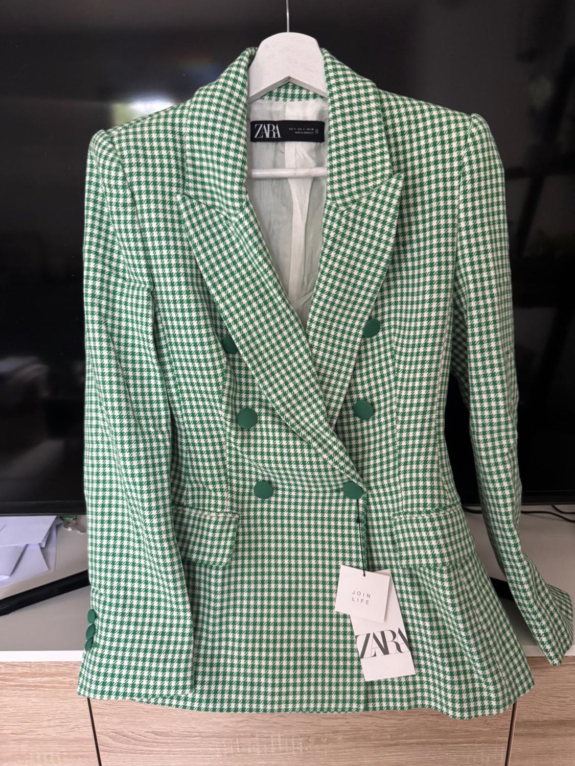Double-breasted blazer with a green and white houndstooth pattern on a hanger. Visible text: ZARA, JOIN LIFE.