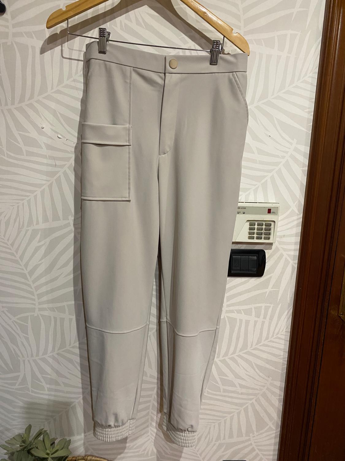 Front view of beige trousers with a side pocket and elasticated cuffs.