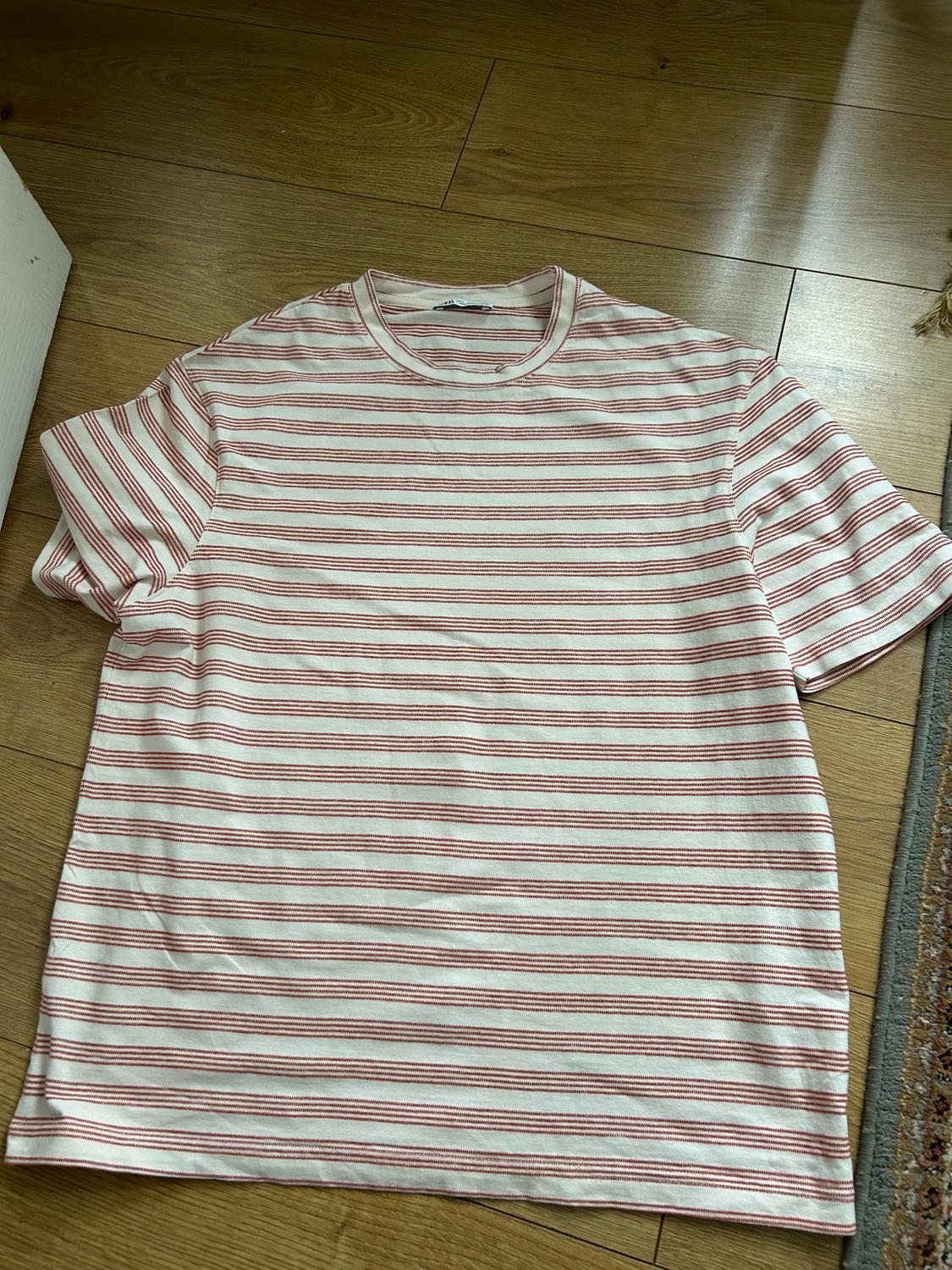 Red and white horizontal striped t-shirt on a wooden floor. Natural light illuminates the scene.