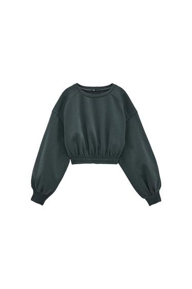 Front view of a dark green cropped sweatshirt with long puff sleeves and an elasticated waistband.