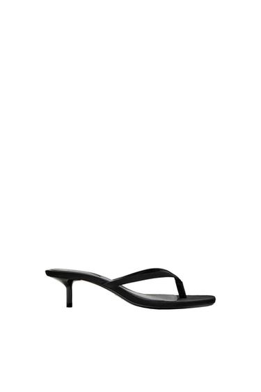 Black sandal with a low heel and minimalist design on a white background.