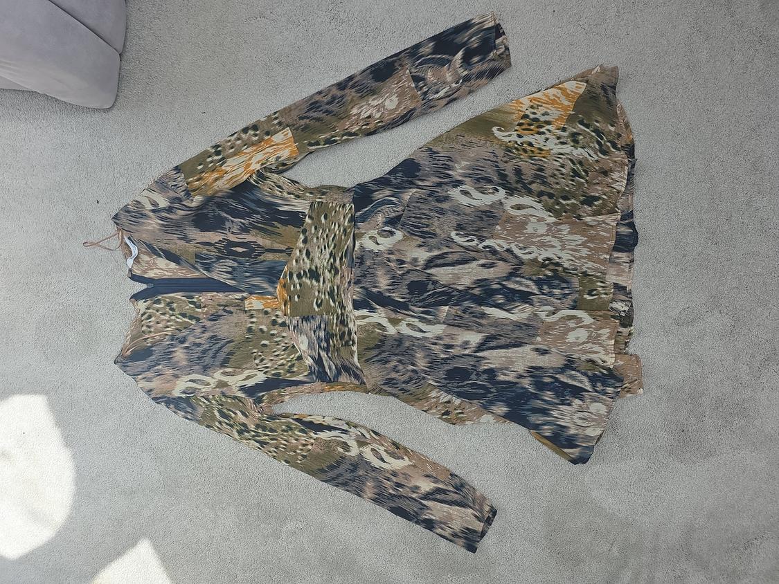 Printed dress with long sleeves and a belt, in brown, green, and black tones, on a light grey rug.