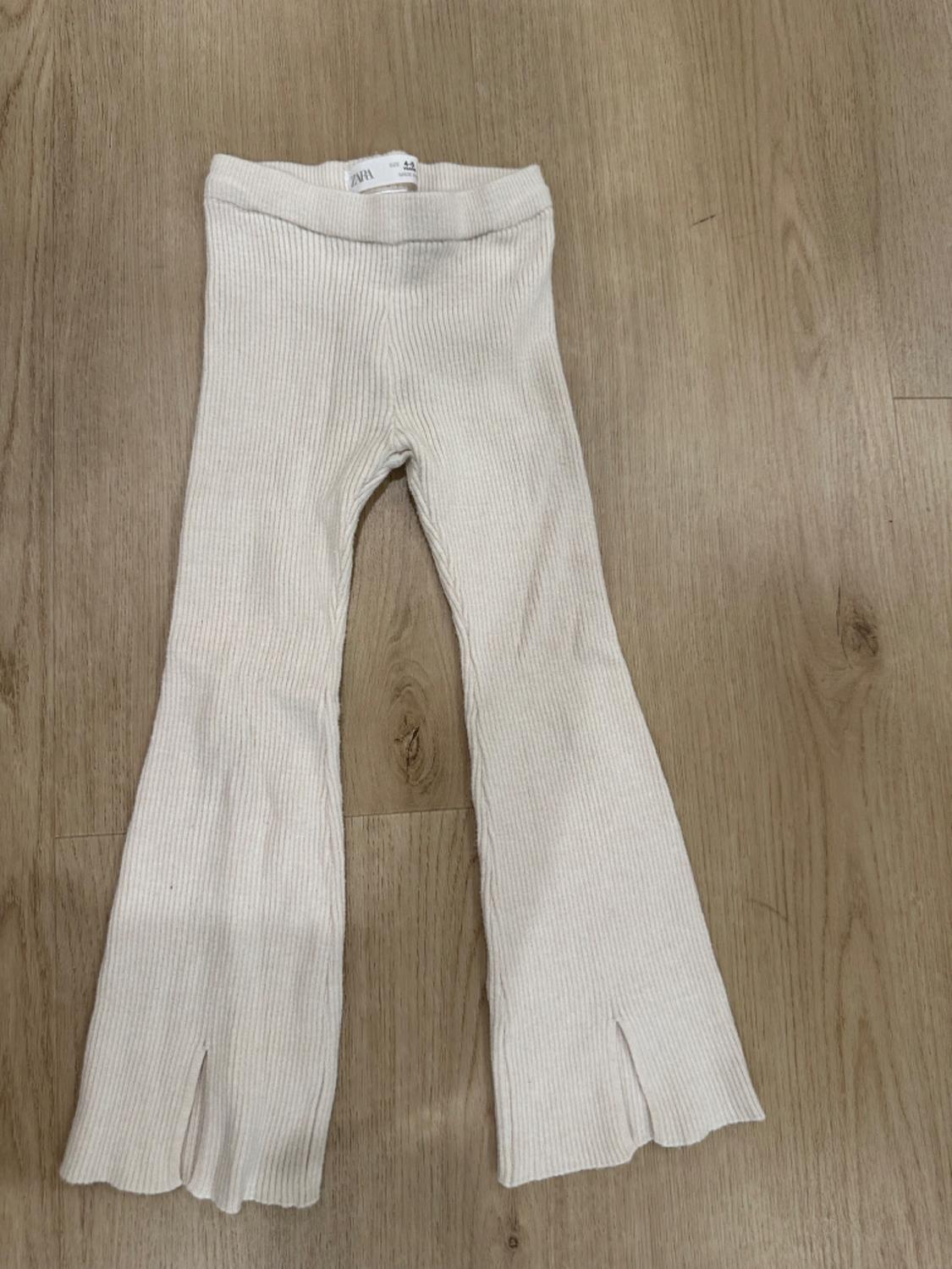 Front view of white flared trousers with split hems.