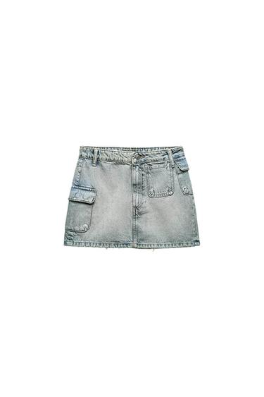 Light blue denim mini skirt with large pockets and a waistband with belt loops. Casual and modern design on a white background.