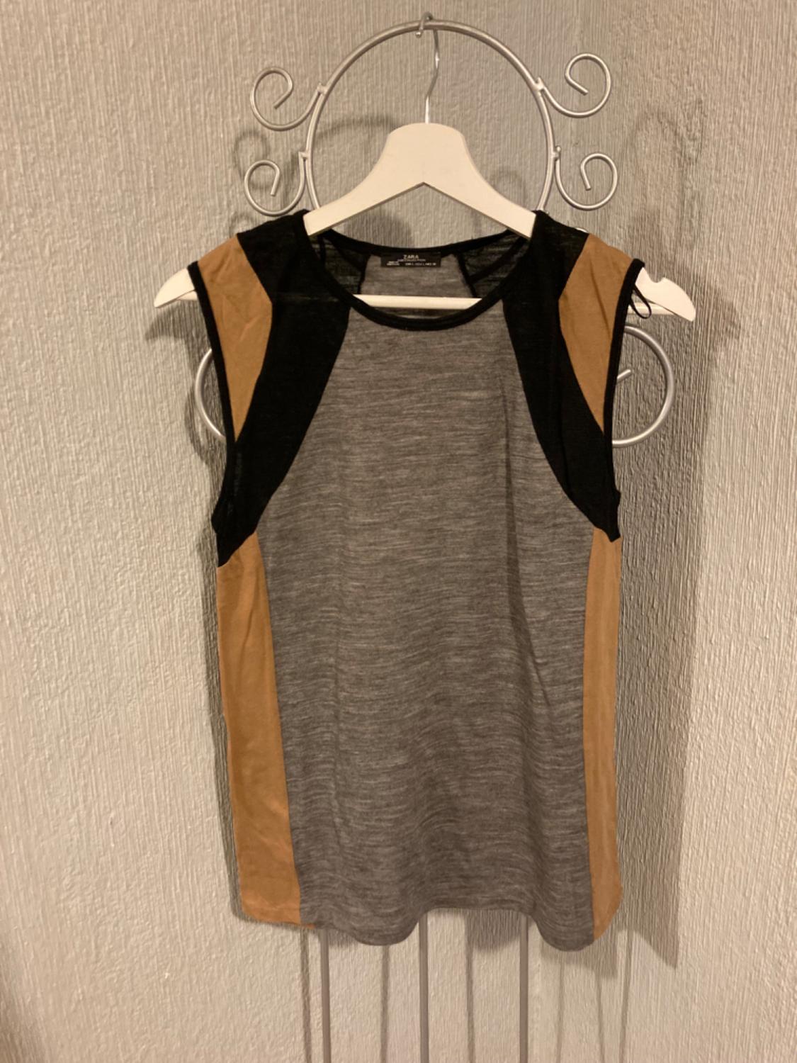Front view of a grey sleeveless t-shirt with black and beige panels, round neck.
