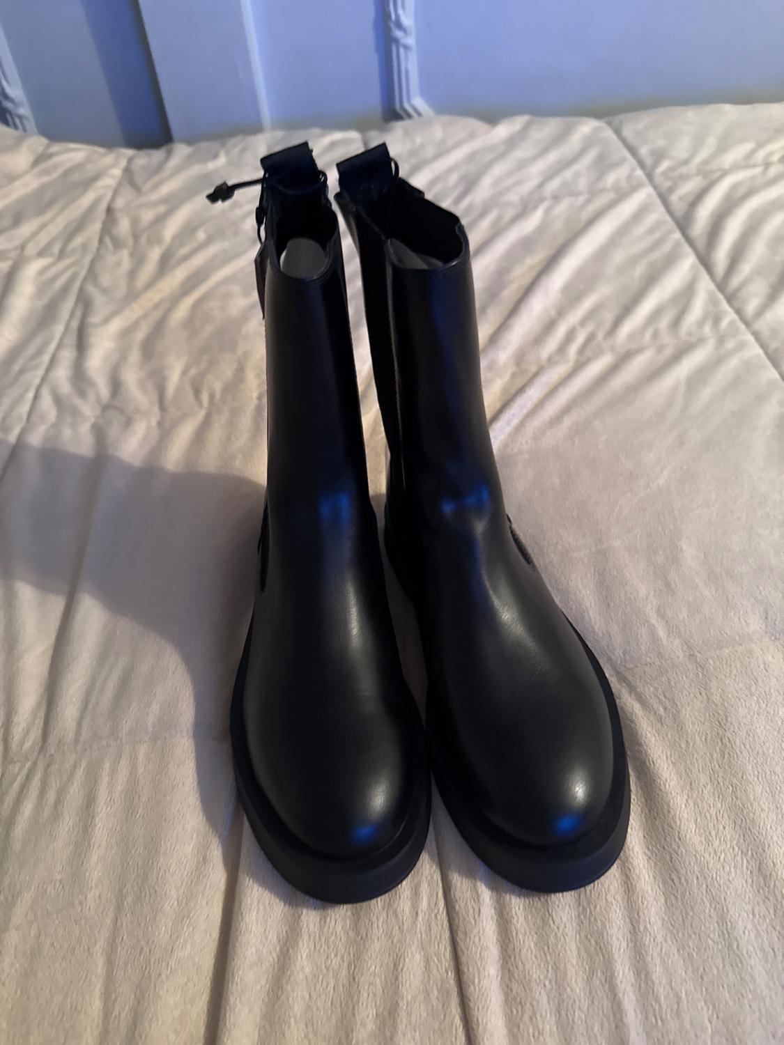 Front view of black boots with back zip on a light surface.