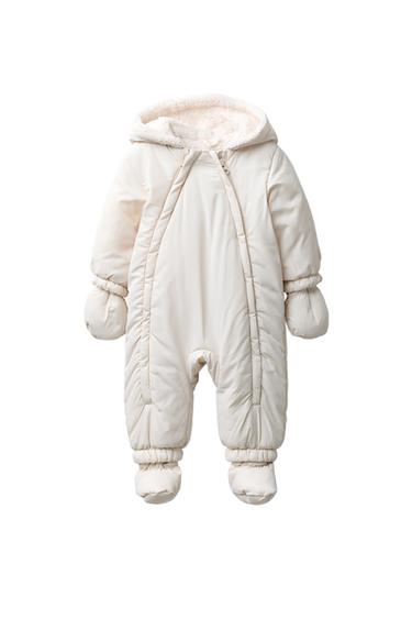 Front view of an ecru raw jumpsuit with hood, zipper closure, detachable mittens and booties, visible inner lining.