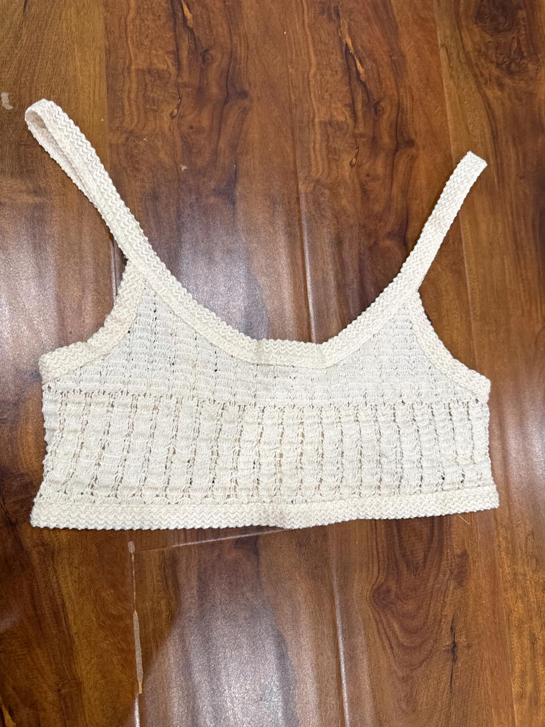 Knitted cami top in cream colour on a dark wood floor.