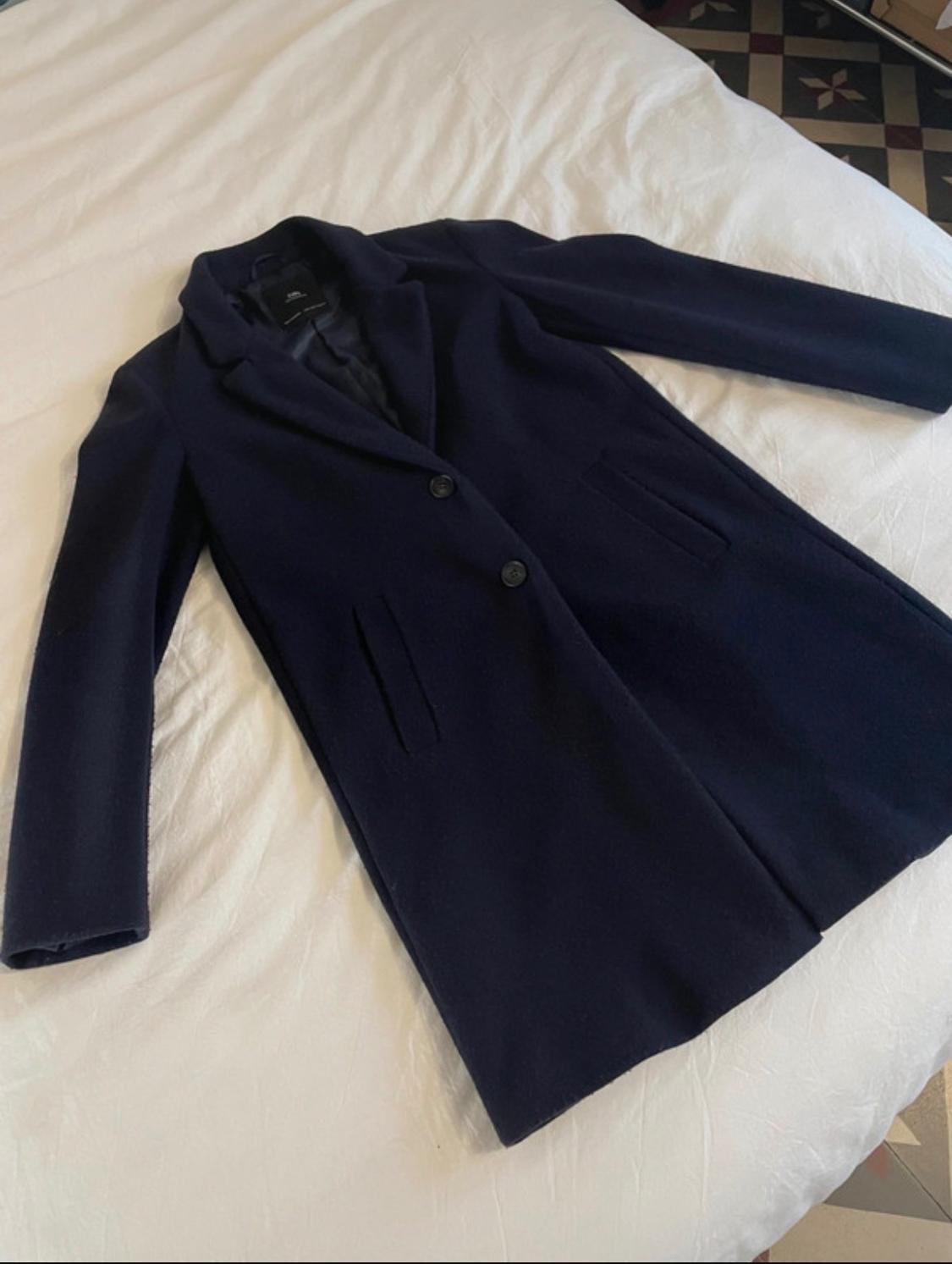 Navy-blue coat with lapels, buttons and front pockets, laid out on white sheets.