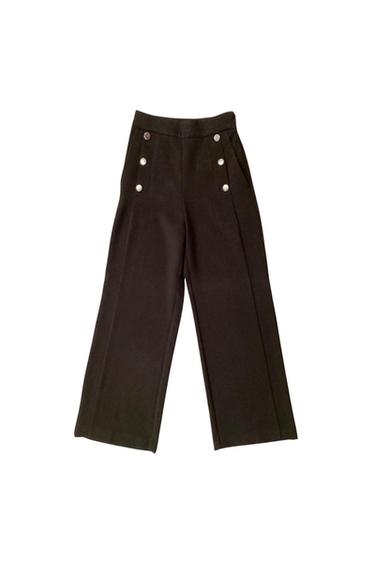 Front view of black pants with decorative buttons and side pockets.